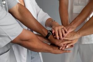 Health care providers placing hands together representing teamwork in community health care